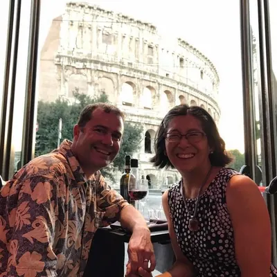 Irene and her husband at a café window facing the Colosseum, Rome.