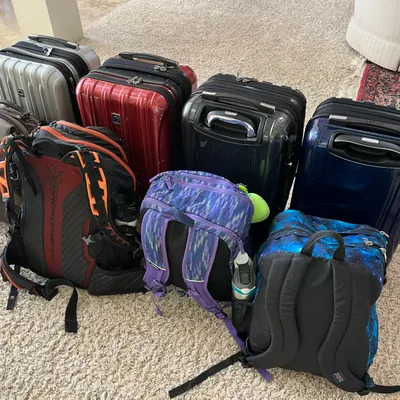 A family’s suitcases and backpacks lined up on a rug, packed and ready to go.