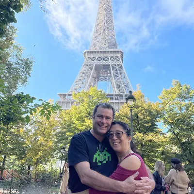 Irene and her husband hugging beneath the Eiffel Tower, Paris.