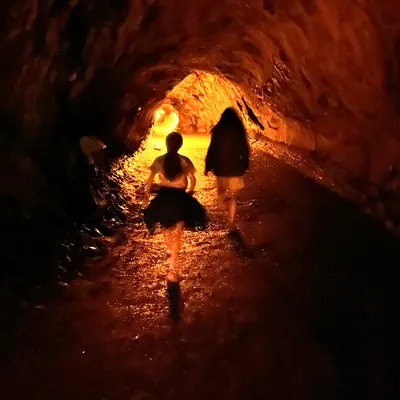 Two children walking through a lava tube toward a glowing light.